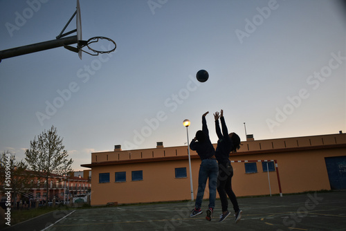 Silhouette of children playing basketball in the yard