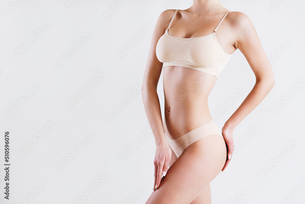 Close up shot of unrecognizable fit woman posing over isolated white background. Torso of slim female with flat belly in white underwear showing her smooth skin after applying skincare. Copy space. Close up shot of unrecognizable fit woman posing over isolated white background. Torso of slim female with flat belly in white underwear showing her smooth skin after applying skincare. Copy space.