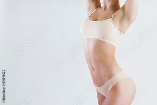 Cropped shot of unrecognizable fit woman in lingerie isolated on white background. Torso of slim attractive female with flat belly in white underwear. Copy space for text, close up.