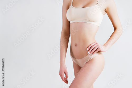 Close up shot of unrecognizable fit woman in lingerie isolated on white background. Torso of slim attractive female with flat belly in beige underwear. Copy space for text.