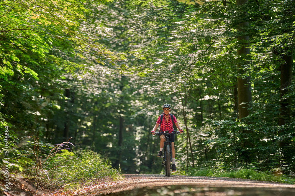 Obraz premium nice active senior woman riding her electric mountain bike in the green city forest of Stuttgart, Germany
