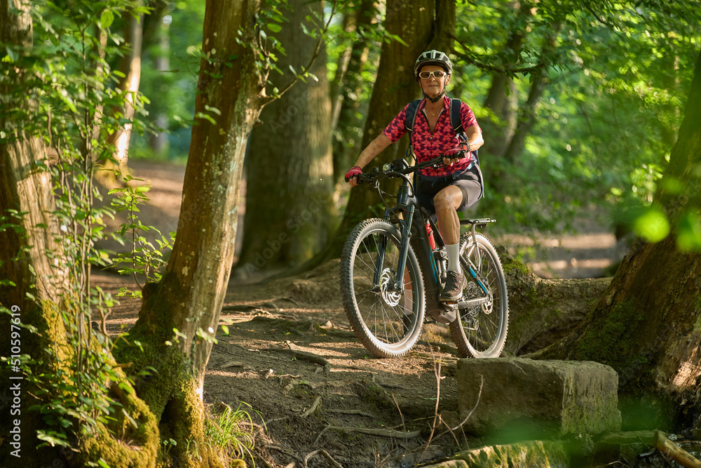 Naklejka premium nice active senior woman riding her electric mountain bike in the green city forest of Stuttgart, Germany 