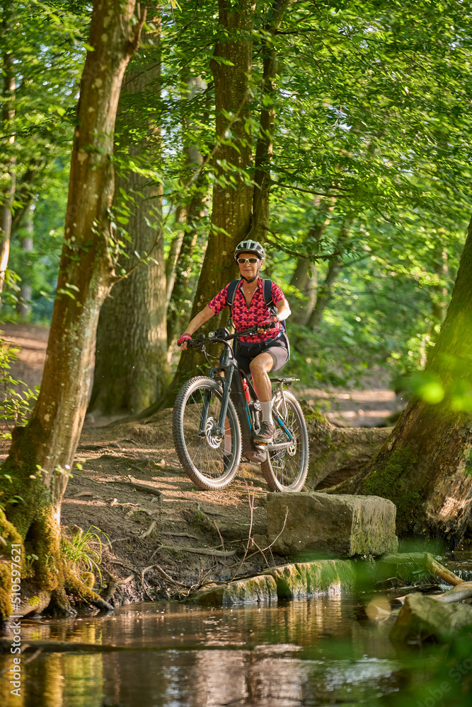 nice active senior woman riding her electric mountain bike in the green city forest of Stuttgart, Germany
