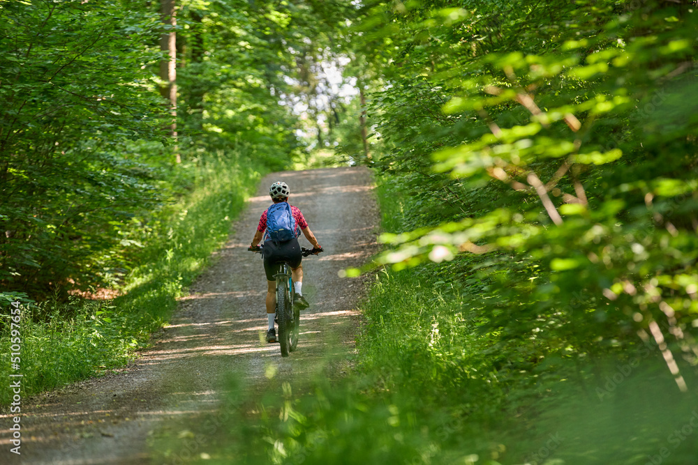 nice active senior woman riding her electric mountain bike in the green city forest of Stuttgart, Germany