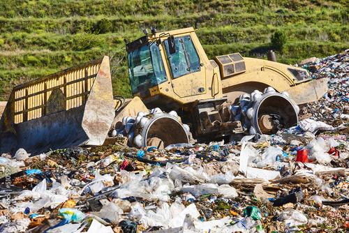 Heavy machinery shredding garbage in an open air landfill. Waste