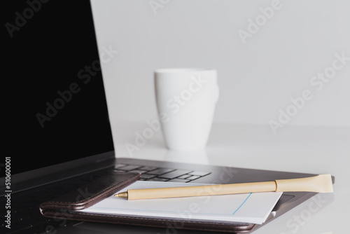 Mock up blank screen laptop and cup of coffee with other office supplies.