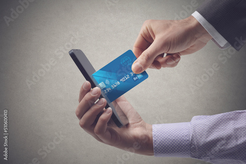 Fototapeta Naklejka Na Ścianę i Meble -  Businessman taking a credit card from a user's phone
