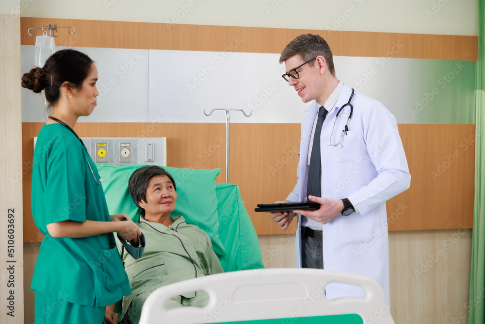 Obraz premium Elderly woman patient on hospital bed and man doctor with nurse. doctor talking consulting and checkup by stethoscope with patient. Hospital Healthcare and medicine concept.