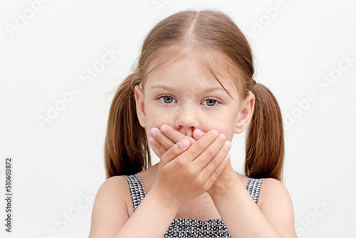 Child holding crossed hands on mouth