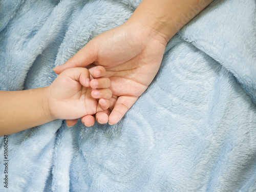 Asian parent hands holding newborn baby fingers, Close up mother's hand holding their new born baby. © Kunlathida