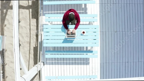 Male freelancer working on a laptop while sitting in a cafe on vacation.