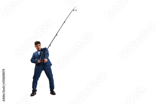 Portrait of young man, employee in official suit with fishing rod isolated over white studio background. Catching profitable projects.