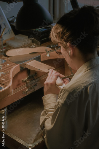 Master of jewelry. Side view of a female jeweler at her workbench. Working desk for craft jewelry making professional tools.