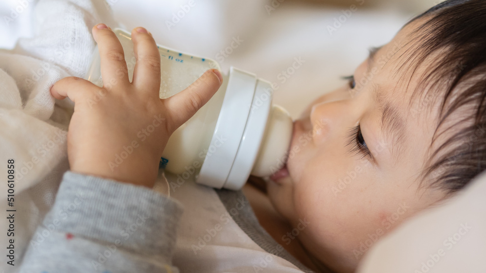 Asian Chinese baby boy age 1 to 2 drinking milk with holding milk bottle by him self. Asian Chinese baby boy age 1 to 2 drinking milk with holding milk bottle by him self.