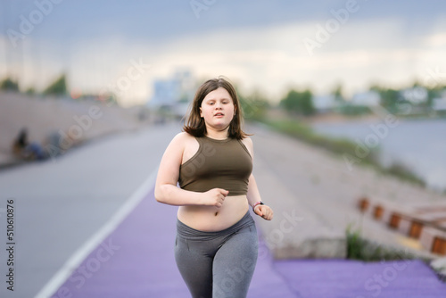 Foto European teenage girl overweight on jog on treadmill along embankment of city, o