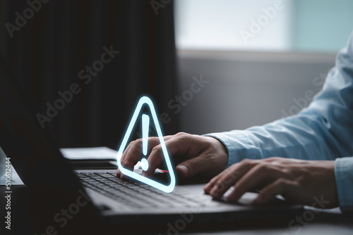 Businessman using computer laptop with triangle caution warning sing for notification error and maintenance concept. photo