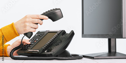 business and communications. Minitor and voip phone in the office, close up of a hand. IP telephony, Cold calling. Audit or accounting. Call center hot line photo