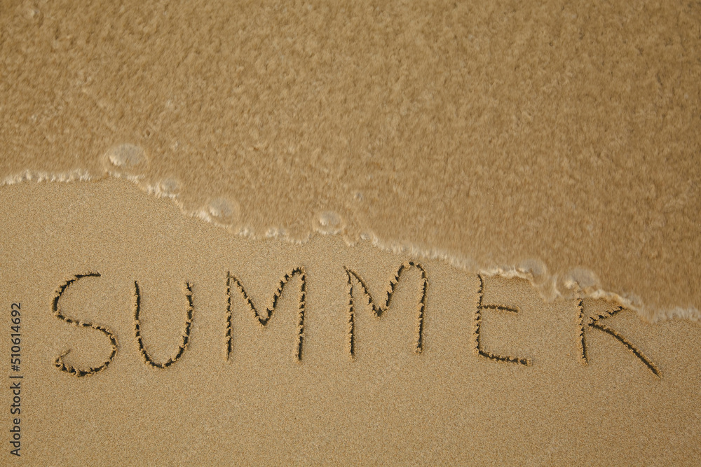 Fototapeta premium Summer - drawing on the soft beach sand with a soft lapping wave.