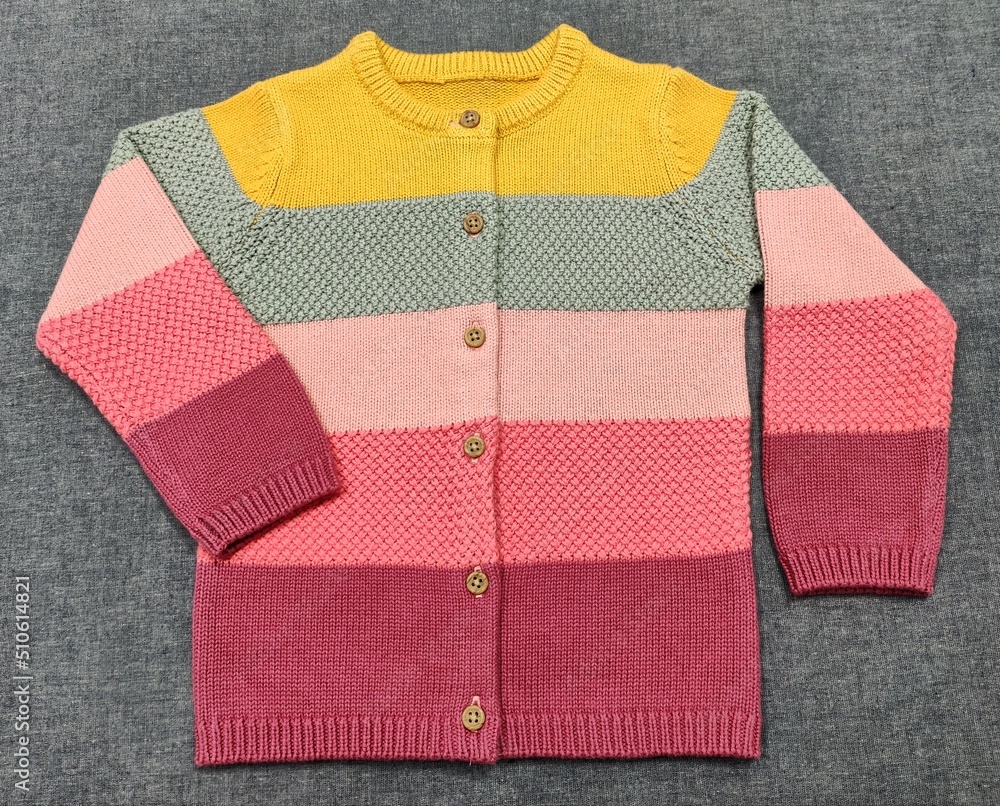 red and white sweater. multi-colour design cardigan, the colour combination of a beautiful sweater has nice match on the grey background. Best quality. Top view red and white sweater. multi-colour design cardigan, the colour combination of a beautiful sweater has nice match on the grey background. Best quality. Top view