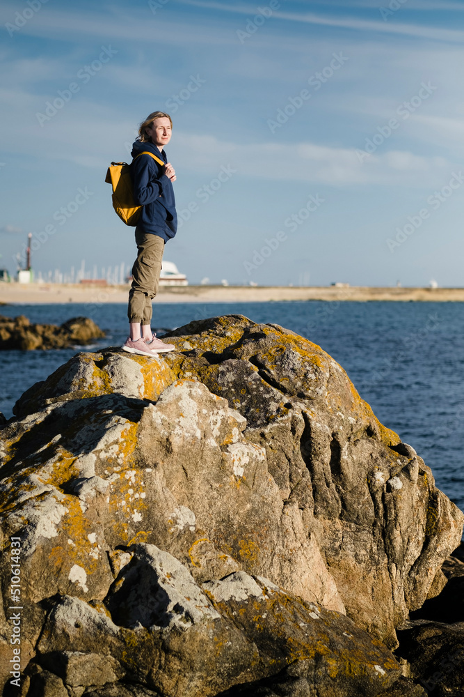 Obraz premium A female tourist with a yellow shoulder bag stands in the harbour.