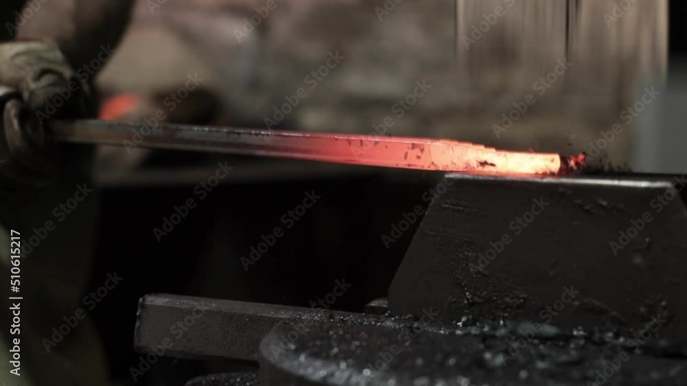 Professional male blacksmith forming red hot metal on an anvil in interior blacksmith workshop. Professional male blacksmith forming red hot metal on an anvil in interior blacksmith workshop.
