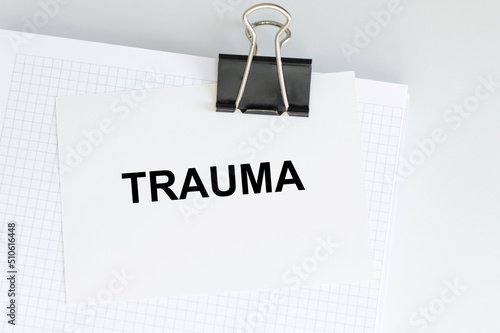 On the business card text TRAUMA on the notepad clip on the table, medical concept