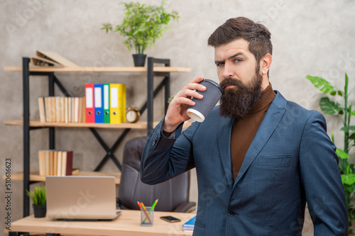 Billede på lærred serious bearded businessman drinking takeaway coffee in the office with copy spa