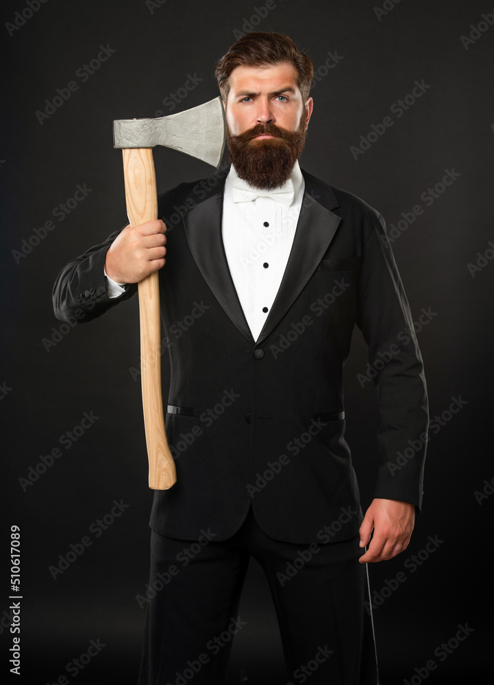 Serious bearded man in formal suit holding axe at unshaven face dark background, barber Serious bearded man in formal suit holding axe at unshaven face dark background, barber
