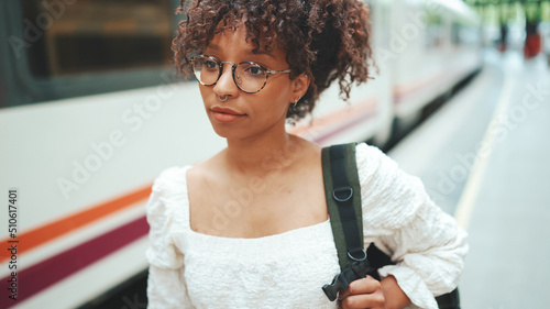 Valokuva close-up portrait of a young woman in glasses with a backpack stands on the plat
