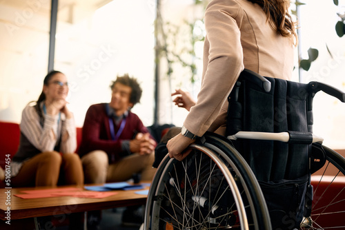 Unrecognizable businesswoman with disability talks to her colleagues in the office. © Drazen