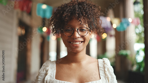 Closeup portrait of a young woman in glasses smiling posing on smartphone selfie camera. Positive woman using mobile phone outdoors in urban background.
