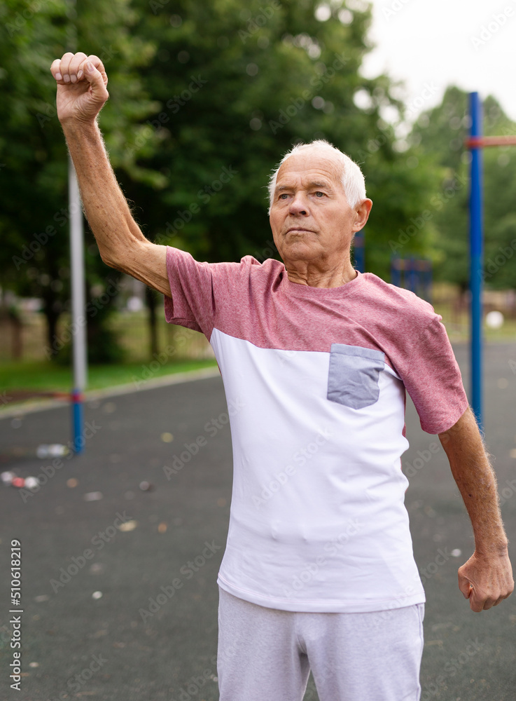 Elderly man doing gymnastic exercises in park