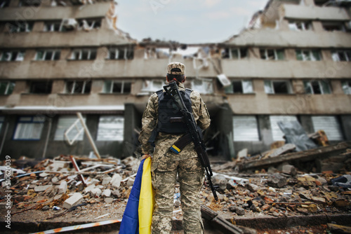 Photographie Ukrainian military woman with the Ukrainian flag in her hands on the background