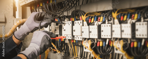 Foto Electricity and electrical maintenance service, Engineer hand holding AC multimeter checking electric current voltage at circuit breaker terminal and cable wiring main power distribution board