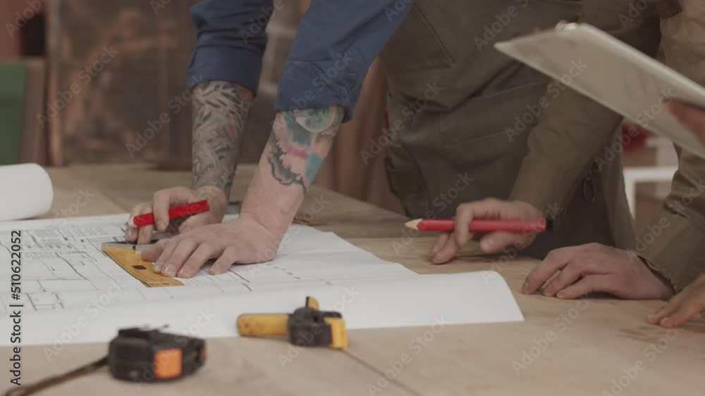 Cropped of unrecognizable woodworkers using ruler and pencil while making design on drawing plan in carpentry workshop Cropped of unrecognizable woodworkers using ruler and pencil while making design on drawing plan in carpentry workshop