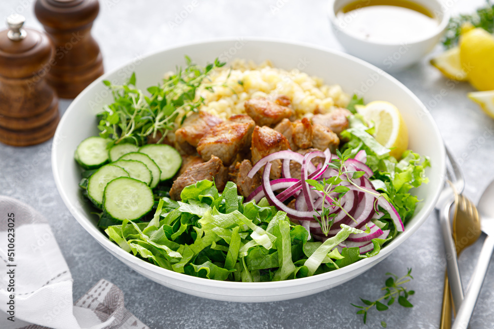 Pork kebab bulgur salad bowl with cucumber, lettuce, thyme and mustard sauce Pork kebab bulgur salad bowl with cucumber, lettuce, thyme and mustard sauce
