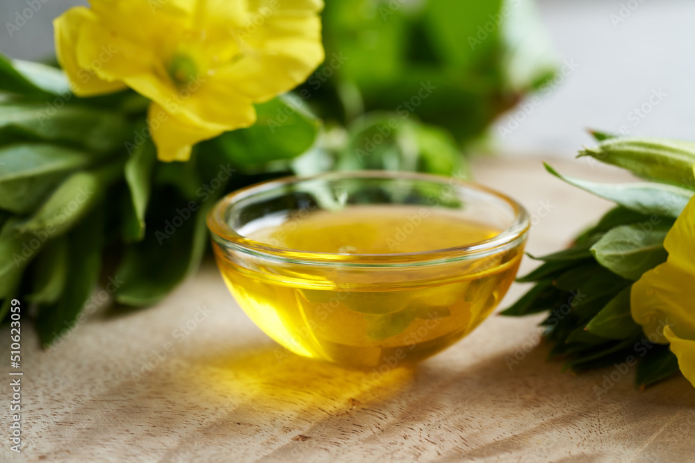 A bowl of evening primrose oil with fresh evening primrose flowers A bowl of evening primrose oil with fresh evening primrose flowers