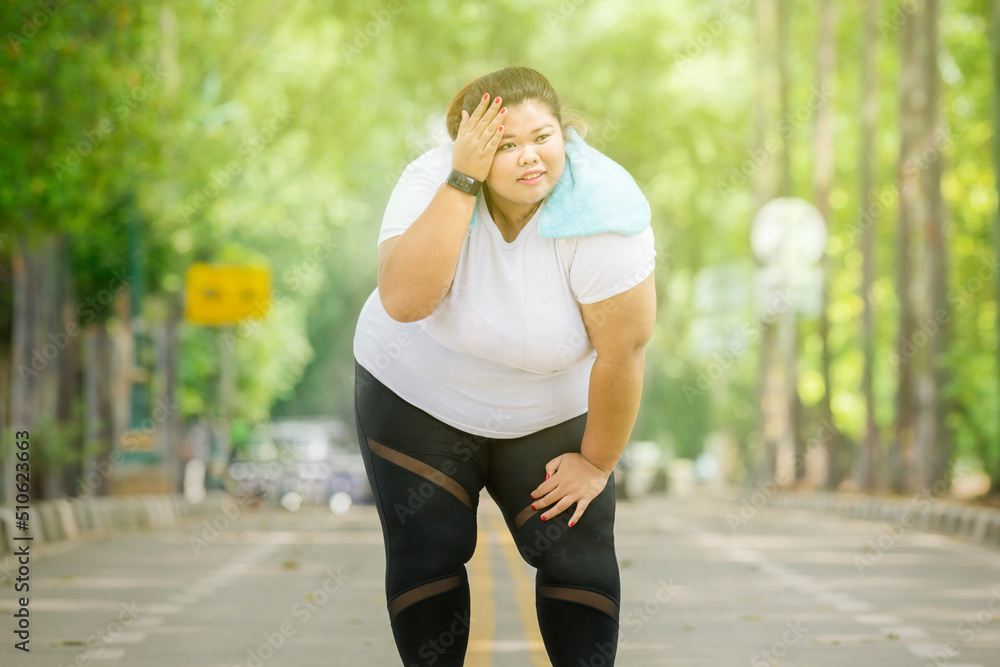 Tired fat woman wiping sweat after running at park Tired fat woman wiping sweat after running at park