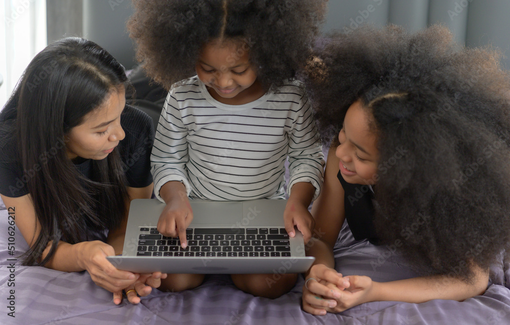 Asian-African American family Use a laptop to surf the Internet and  shop online. On the bed in bedroom in the holiday.
