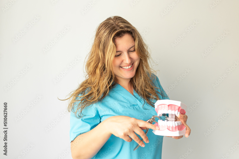 Happy young dentist or surgeon in uniform with jaw and dental nippers Happy young dentist or surgeon in uniform with jaw and dental nippers