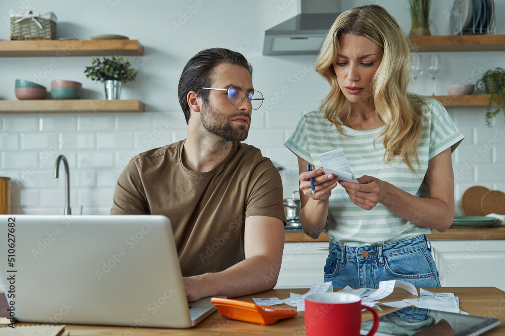 Beautiful young couple going over financial bills while sitting at the domestic kitchen Beautiful young couple going over financial bills while sitting at the domestic kitchen