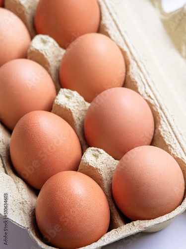 Vertical photo of brown uncooked unwased chiken eggs in a carton