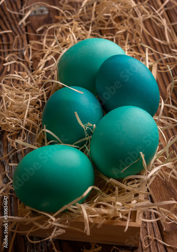 Colorful easter eggs on hay. Bright and colorful eggs on wooden background