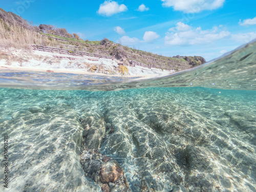 Split underwater view of sand and rocks in La Speranza beach