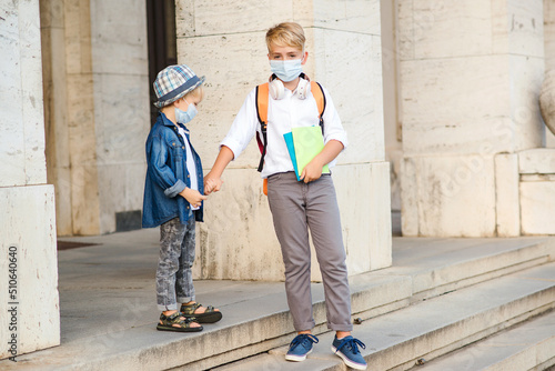 School kids wearing face mask during coronavirus outbreak. Children going home after school.