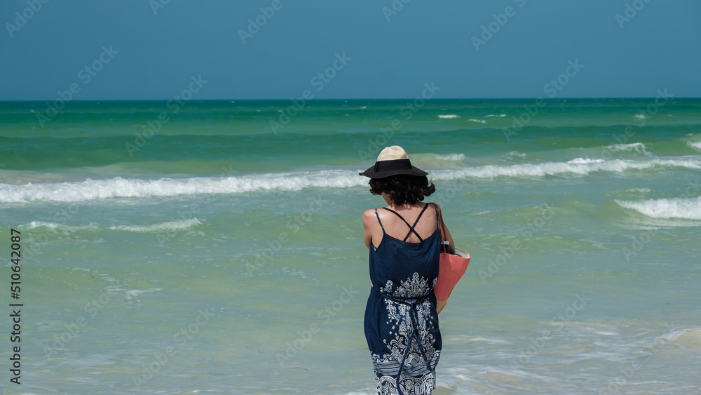 Woman with panama walking on the beach of the Caribbean Sea
