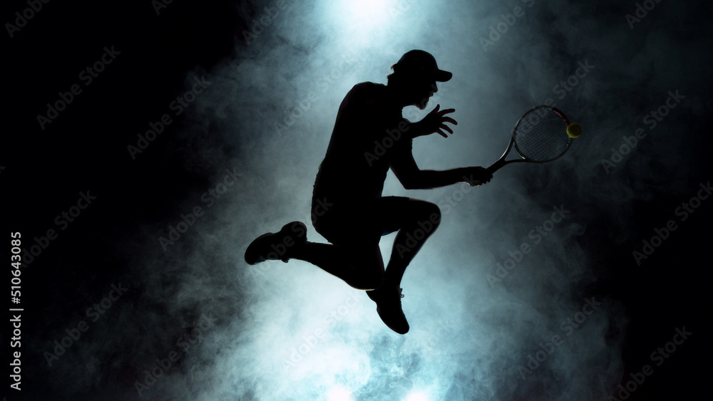 Dramatic tennis player silhouette jumping up in the air Dramatic tennis player silhouette jumping up in the air