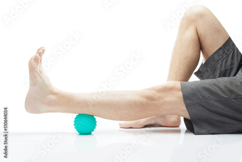 Close-up low section of man standing over massage ball against white background