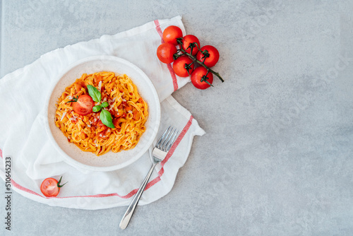 Tableau sur toile Top view plate of just cooked homemade fettuccine pasta with creamy tomato sauce, seafood and parmesan cheese, decorated with basil leaves on the grey stone background