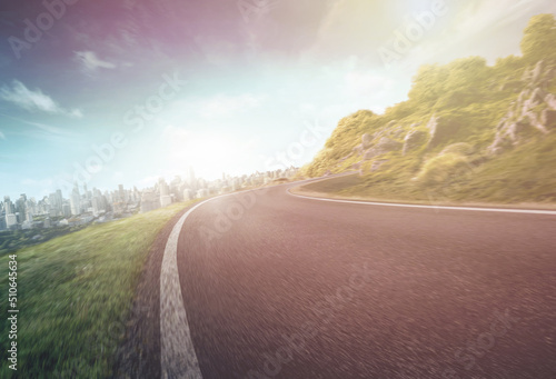 Empty long mountain road to the horizon on a sunny summer day at a bright sunset - speed motion blur effect.